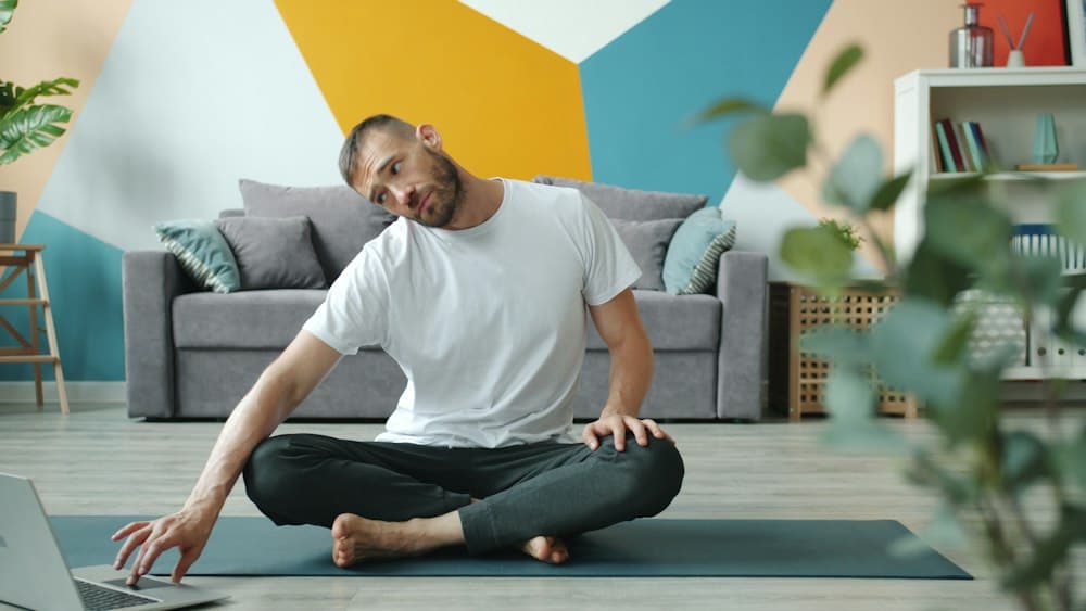 A member stretches on their mat in front of their computer